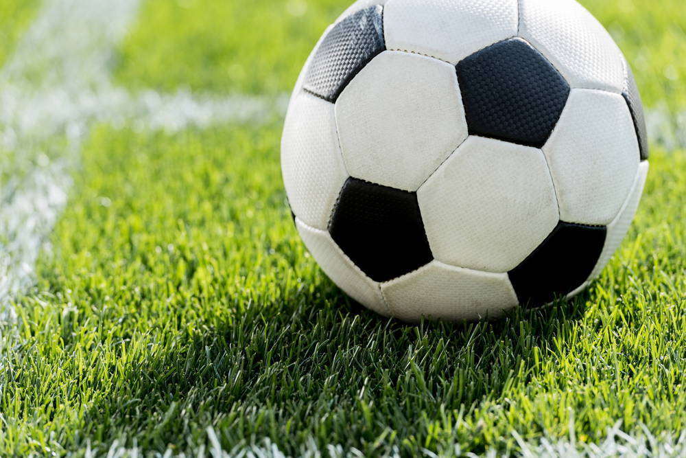 Soccer ball resting on bright green grass with a white sideline in the background.