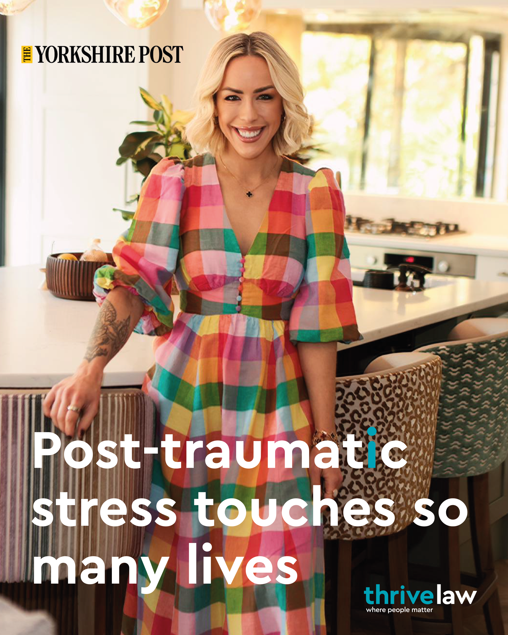 Smiling woman in a colorful plaid dress stands in a bright kitchen on a magazine cover about post-traumatic stress and resilience.