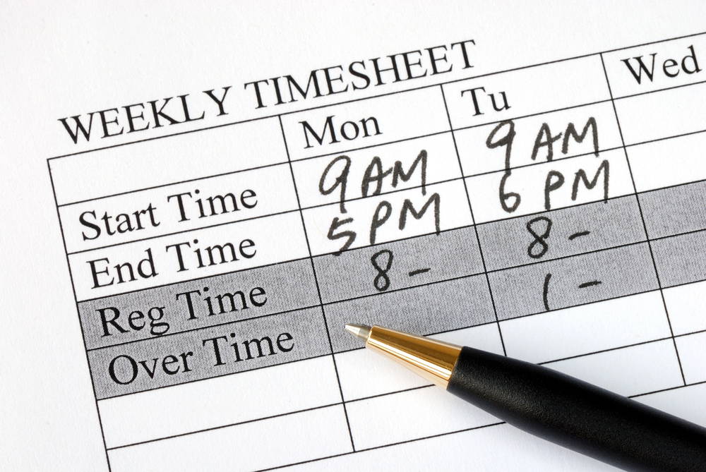 Close-up of a weekly timesheet with handwritten start/end times and a black-and-gold pen resting on it